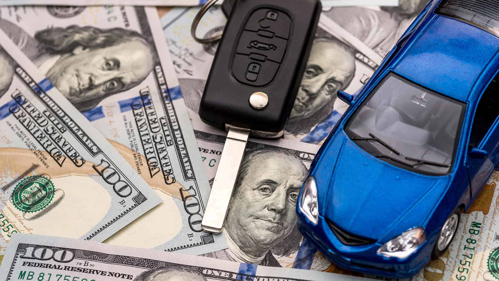 car keys and model car laying on 100 dollar bills