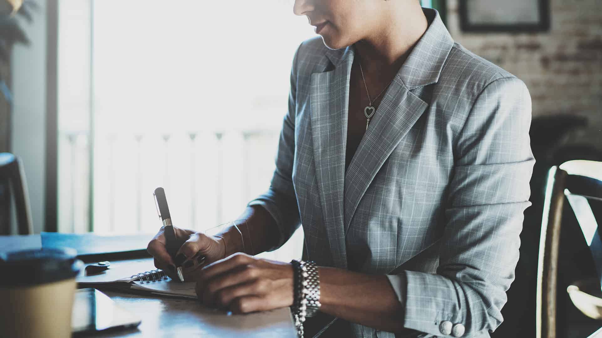 NAMG-2019.09-1920x1080_181495554 Image of young businesswoman writing something in note pad while sitting