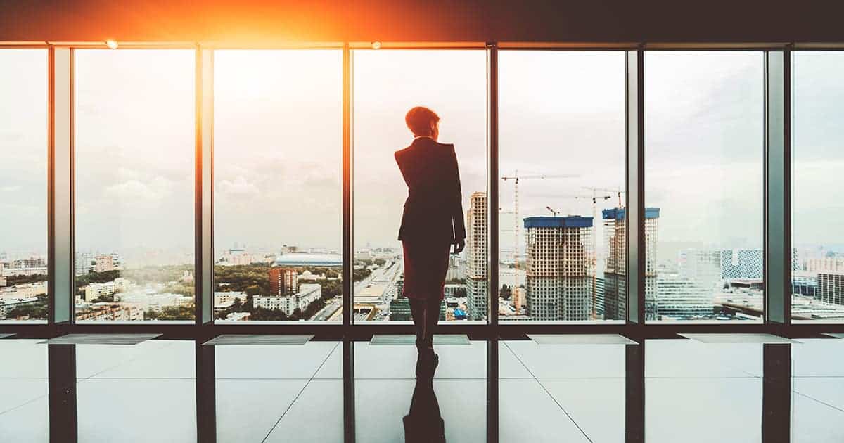 silhouette of businesswoman on the top of a modern business office skyscraper standing near big panoramic windows