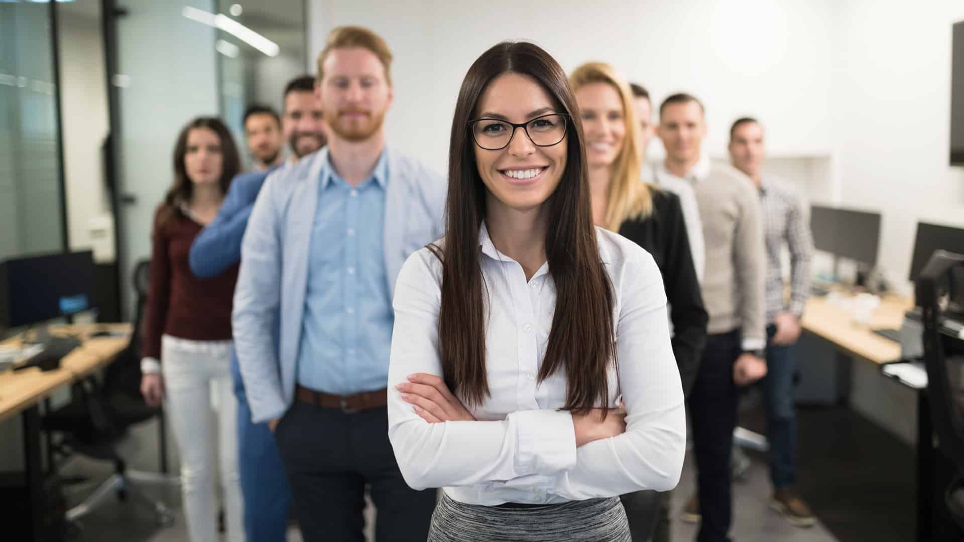 business team posing in an office with a female in the front