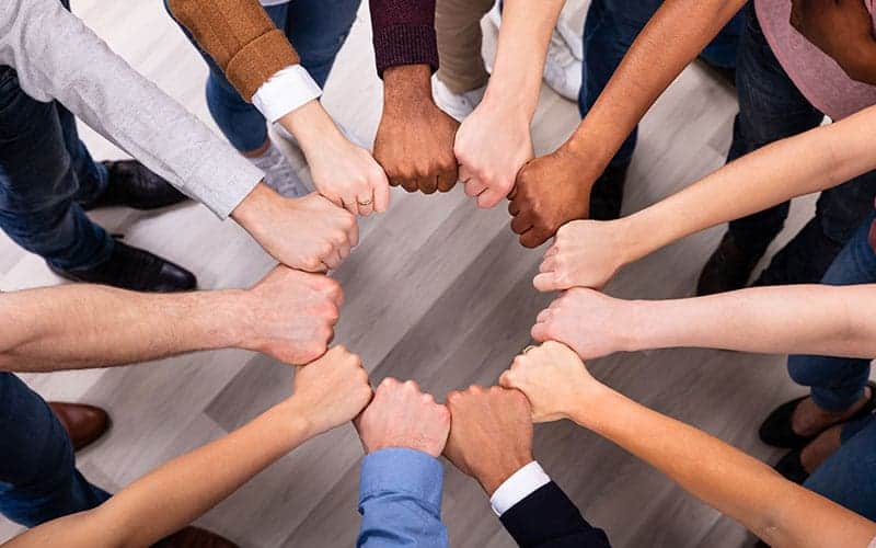 People coming together and holding fist in circle
