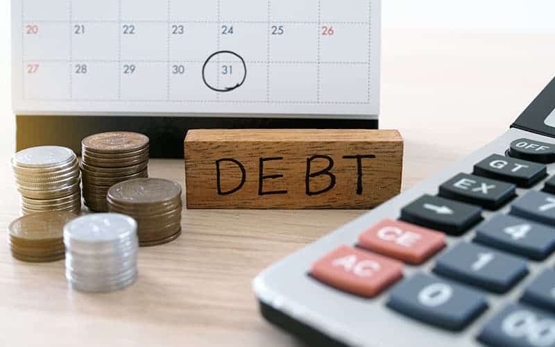 An image with a calendar, coins, calculator, and a rectangular wood written debt on it