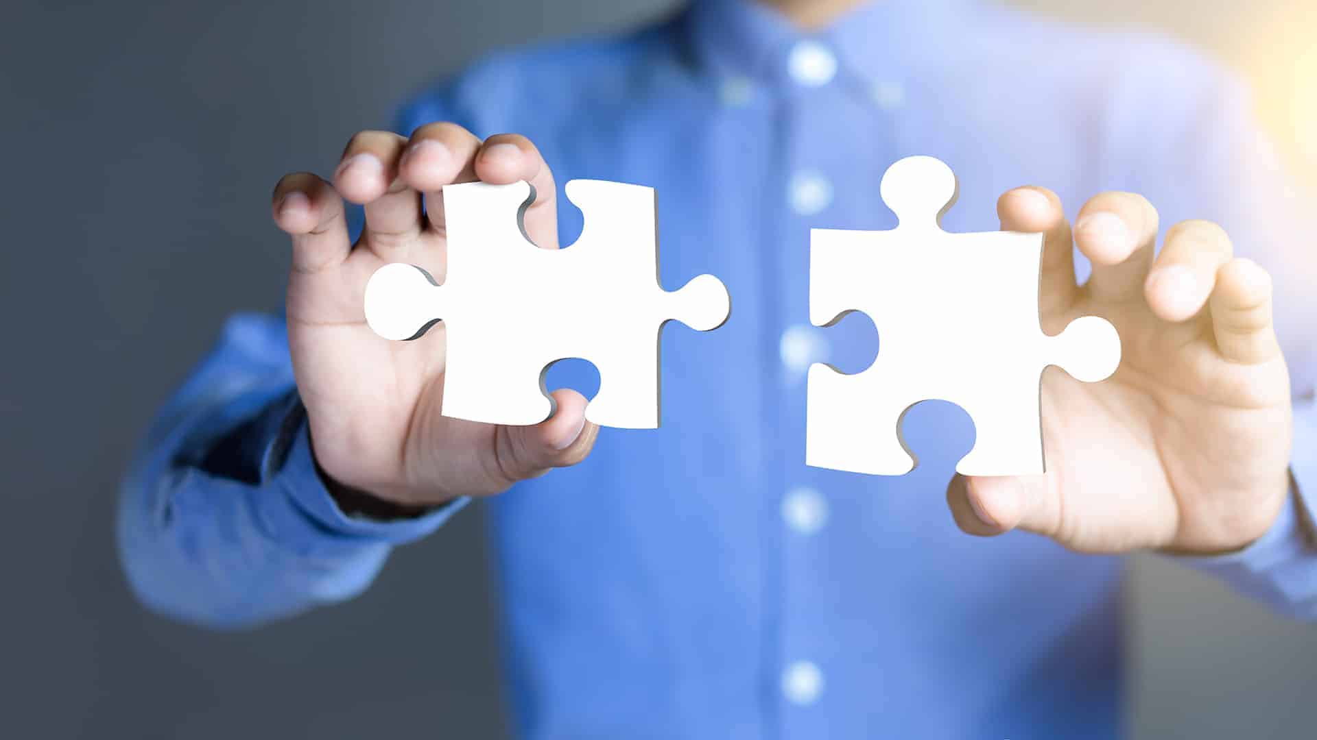 Businessman hands connecting puzzle pieces representing the merging of two companies