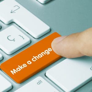 Man pressing a red button on a keyword which says make a change
