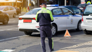 Road traffic inspector examines car crash site with damaged vehicle