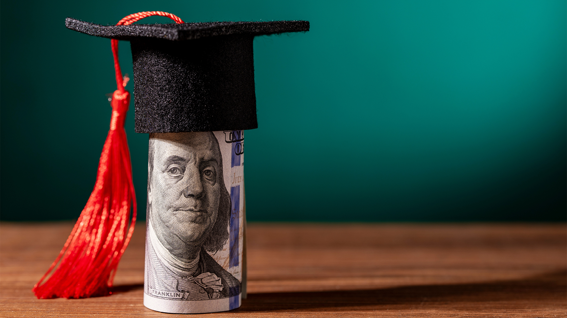 Graduation cap on hundred dollar bill.